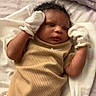 Ka Lani joined the competition — help win amazing prizes! baby, infant, newborn, mittens, onesie, lying_down, blanket, bed, curly_hair, person, indoors, soft_fabric, cute, sleepwear, resting, child, skin, face, handwear, cozy