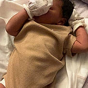 Ka Lani is registered to the contest to win money with this photo: baby, infant, mittens, beige_outfit, sleeping, lying_down, curly_hair, soft_surface, blanket, bed, peaceful, cute, child, newborn, clothing, indoor, resting, cozy, small_arms, closeup