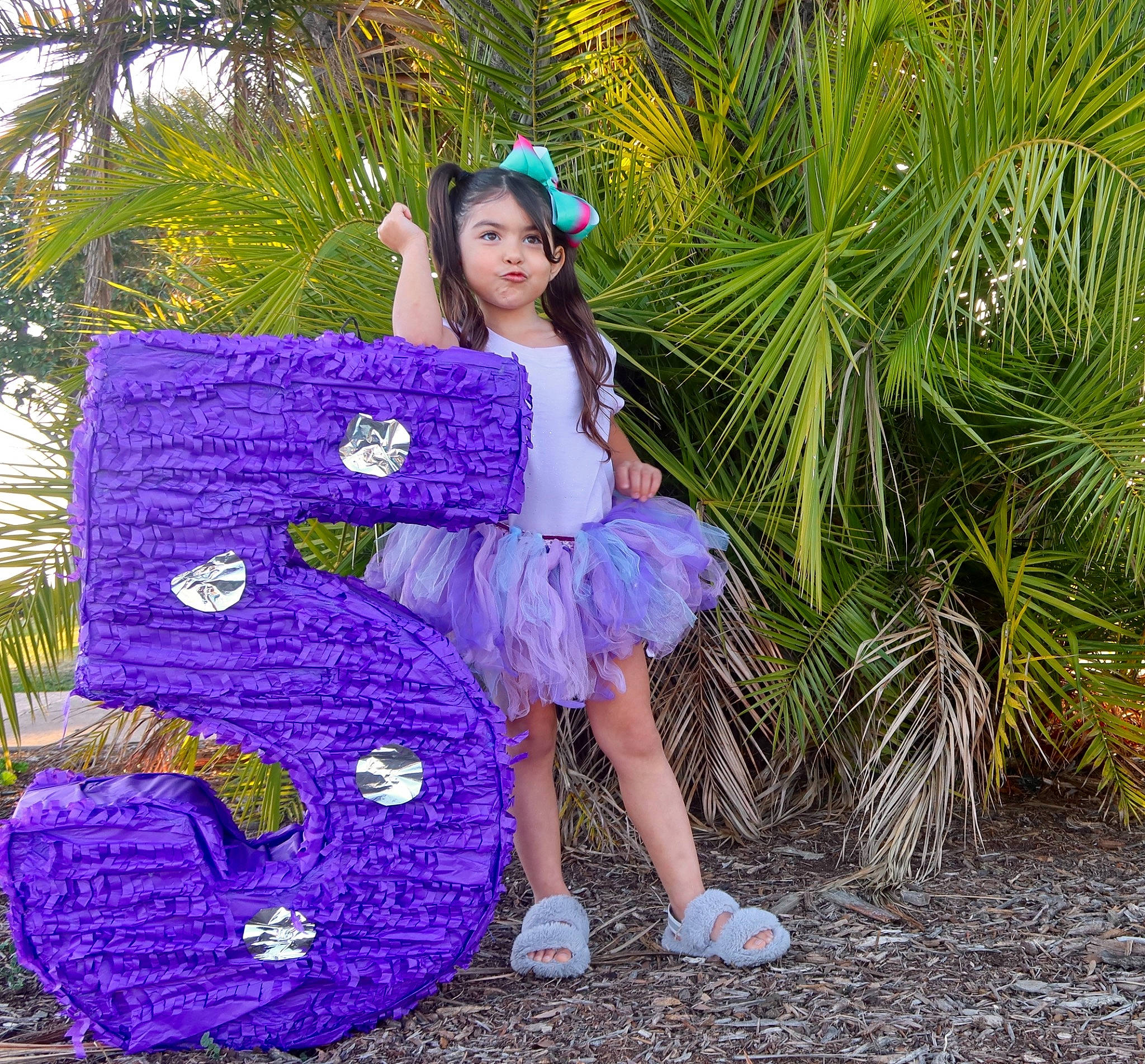 Chloe is registered to the contest to win money with this photo: arecales, botany, electric_blue, fawn, garden, grass, green, hime_cut, magenta, mythical_creature, palm_tree, people_in_nature, person, pink, plant, purple, sandal, sitting, terrestrial_plant, tree