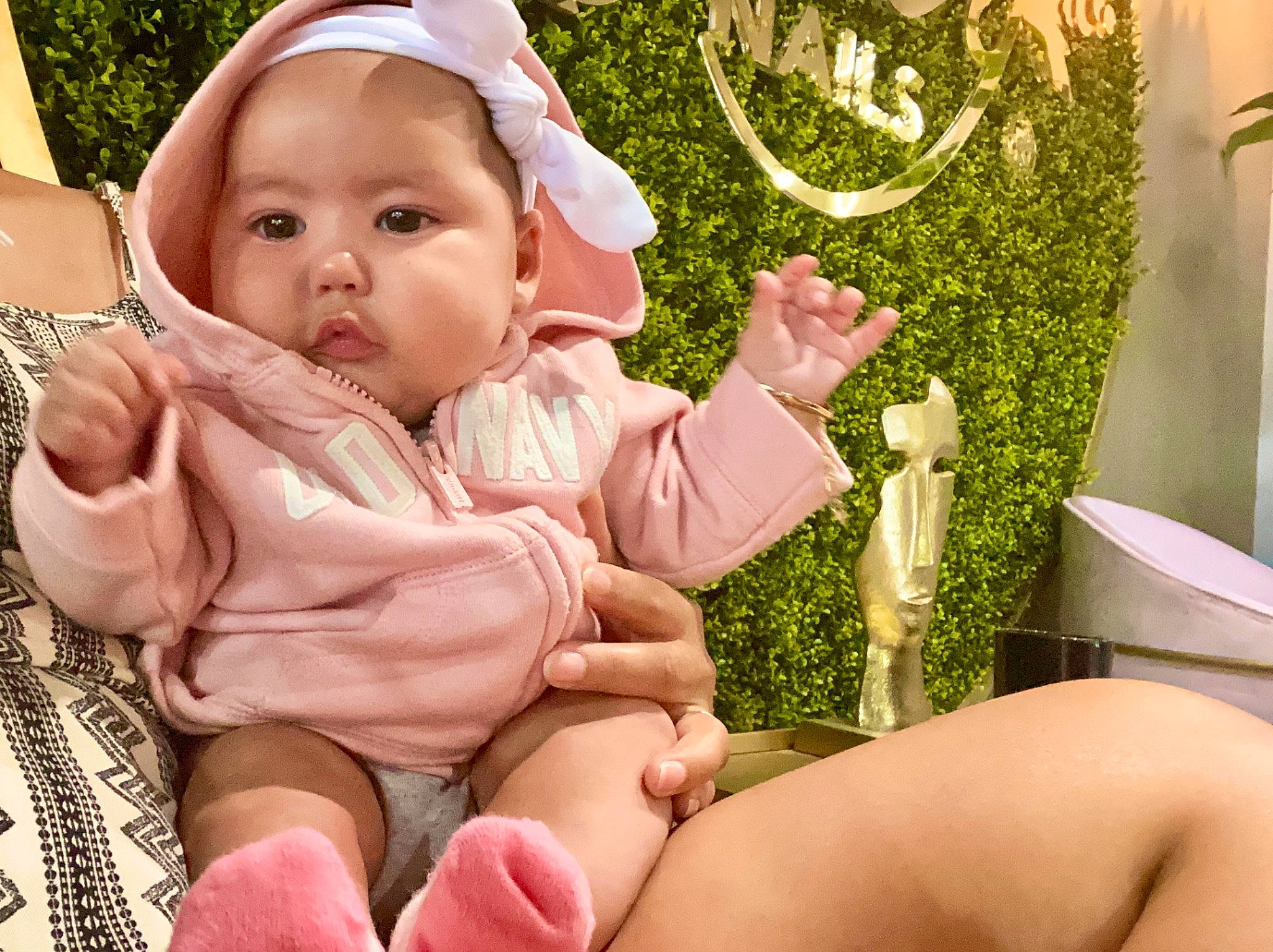 Celine is registered to the contest to win money with this photo: baby, baby_toddler_clothing, comfort, eye, finger, fun, gesture, grass, hand, happy, headwear, lap, leg, mouth, people_in_nature, person, pink, skin, summer, thigh