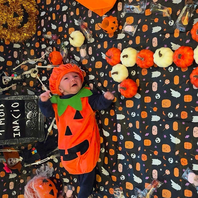 Inacio participe au concours pour gagner de l'argent avec cette photo : baby, black, blanket, candy, celebration, cute, decorations, face, festive, floor, halloween, holiday, holiday_decoration, infant, orange, pumpkin_costume, seasonal, smiling, toy, white