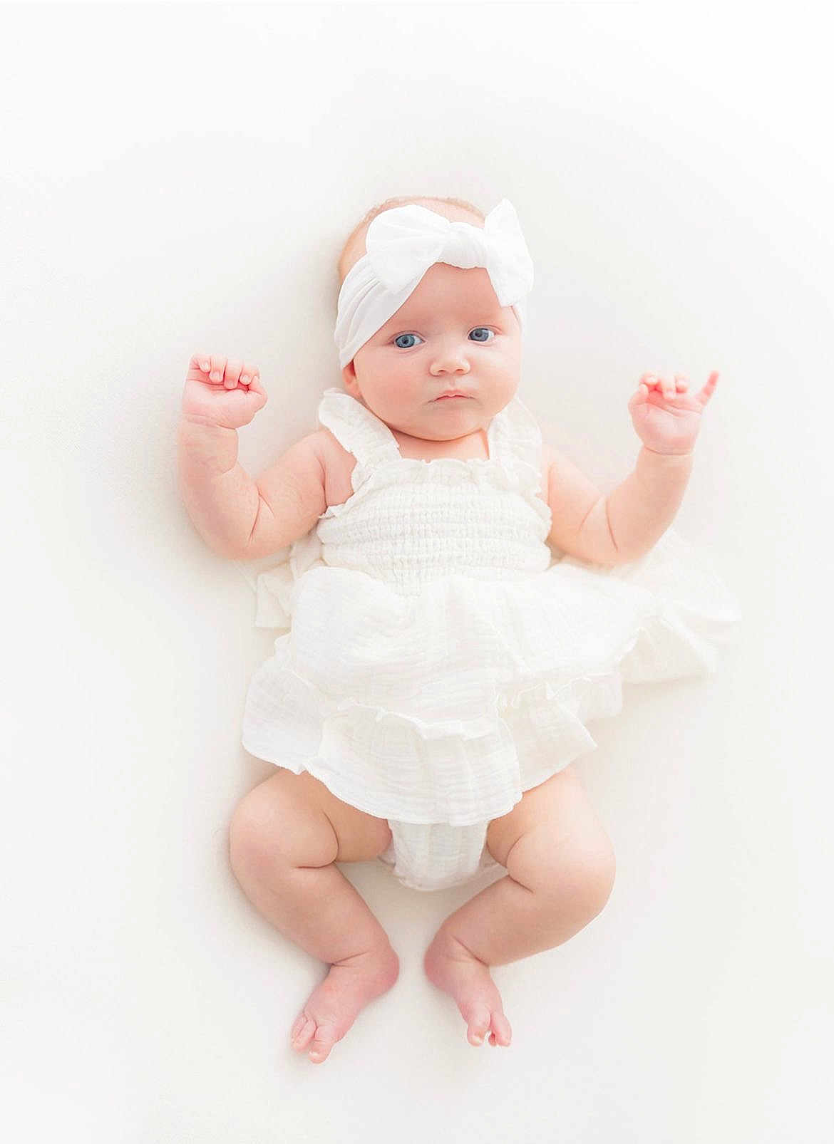 Cassidy is registered to the contest to win money with this photo: baby, infant, white_dress, headband, blue_eyes, cute, lying_down, soft_lighting, high_key, newborn, skin, barefoot, portrait, child, adorable, innocence, baby_fashion, white_background, hands_up, soft_texture