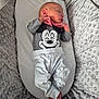 baby, baby_lounger, child, clothing, cozy, cute, gray_shirt, indoor, infant, mickey_mouse, newborn, outfit, peaceful, plush_blanket, portrait, resting, sleeping, small_hands, soft_texture, white_pants