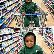 Mylo is registered to the contest to win money with this photo: toddler, child, shopping_cart, green_hoodie, nike, store_aisle, supermarket, personal_care_products, toothpaste, shelves, floor, shopping, baby, portrait, person, clothing, handrail, grocery, cute, indoors
