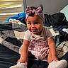 Amelia is registered to the contest to win money with this photo: baby, child, toddler, portrait, smiling, sitting, bedroom, bed, blanket, headband, bow, pink_outfit, overalls, shirt, sneakers, fashion, indoor, window, blinds, happy