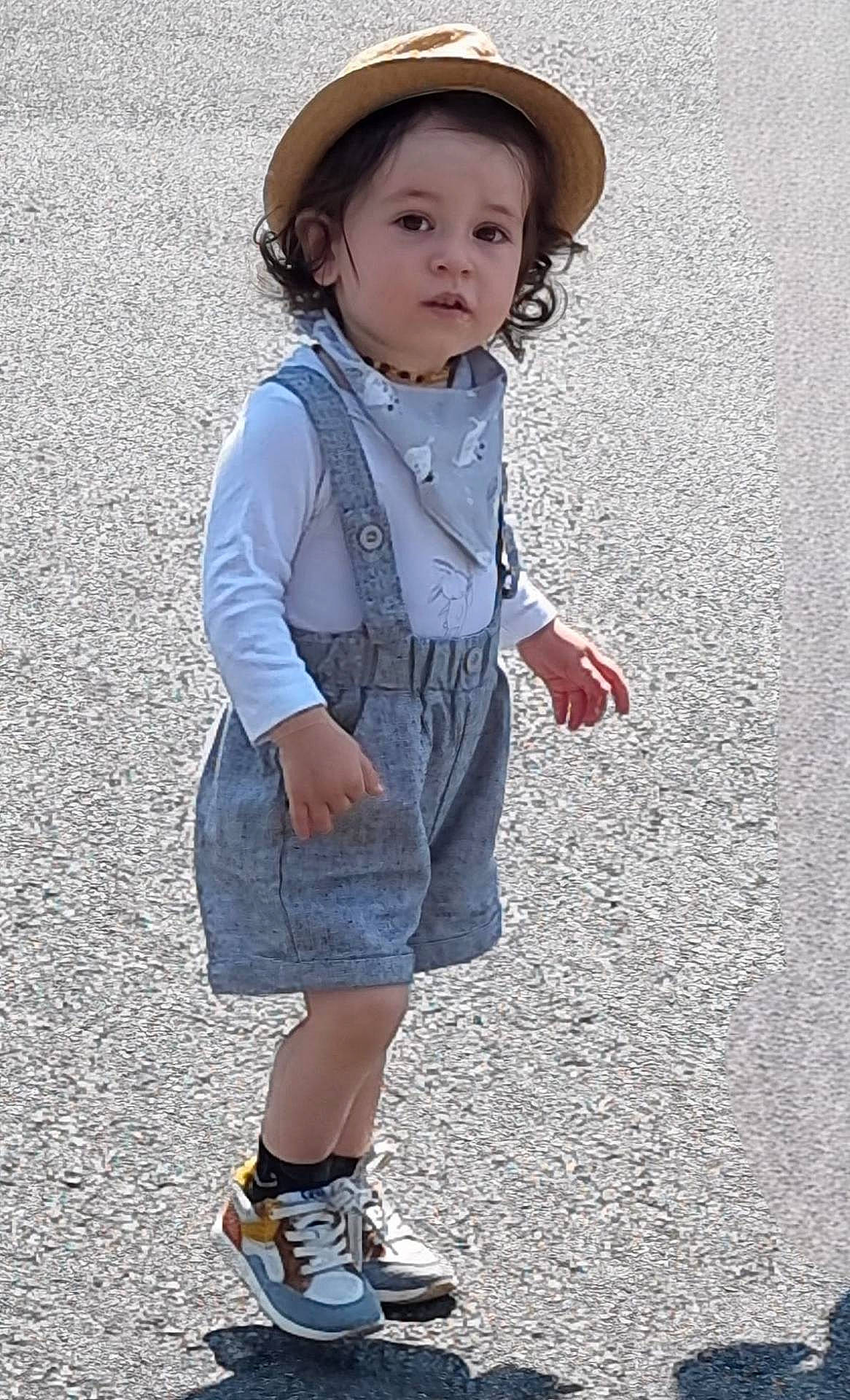 Elliot participe au concours pour gagner de l'argent avec cette photo : bandana, casual_clothing, child, curly_hair, cute, daylight, fashion, hat, outdoor, pants, person, shadow, shirt, sneakers, standing, street, suspenders, toddler, walking, young_child