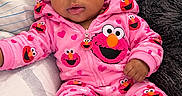 Faith is registered to the contest to win money with this photo: baby, bed, blanket, bow, carpet, child, clothing, elmo, headband, indoor, infant, lying_down, onesie, pajamas, pillow, pink, portrait, smiling, toy, wide_eyed