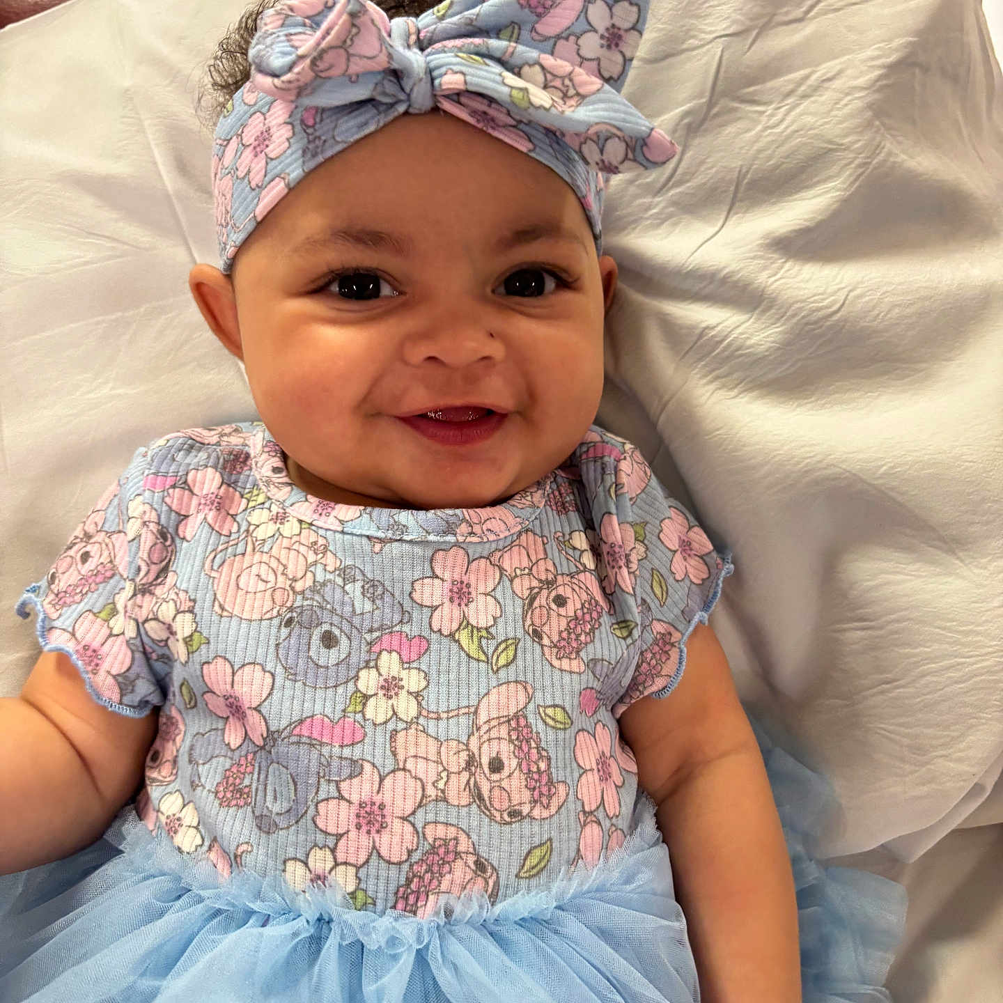 Nyima joined the competition — help win amazing prizes! baby, blue, bow, child, clothing, curly_hair, cute, dress, floral, girl, happy, headband, indoors, infant, lying_down, pink, portrait, skin, smiling, tutu