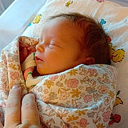 Evelynn is registered to the contest to win money with this photo: newborn, baby, sleeping, blanket, floral_pattern, hand, pillow, cartoon_characters, cute, infant, resting, soft, cozy, indoors, closeup, peaceful, child, person, wrapped, portrait