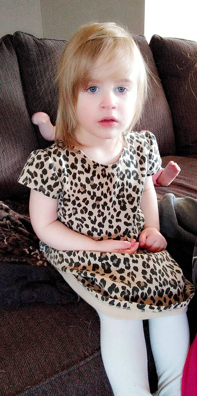 Olivia participe au concours pour gagner de l'argent avec cette photo : baby, baby_toddler_clothing, bangs, blond, brown_hair, child_model, couch, day_dress, feathered_hair, hime_cut, living_room, mammal, nose, pattern, person, sitting, toddler