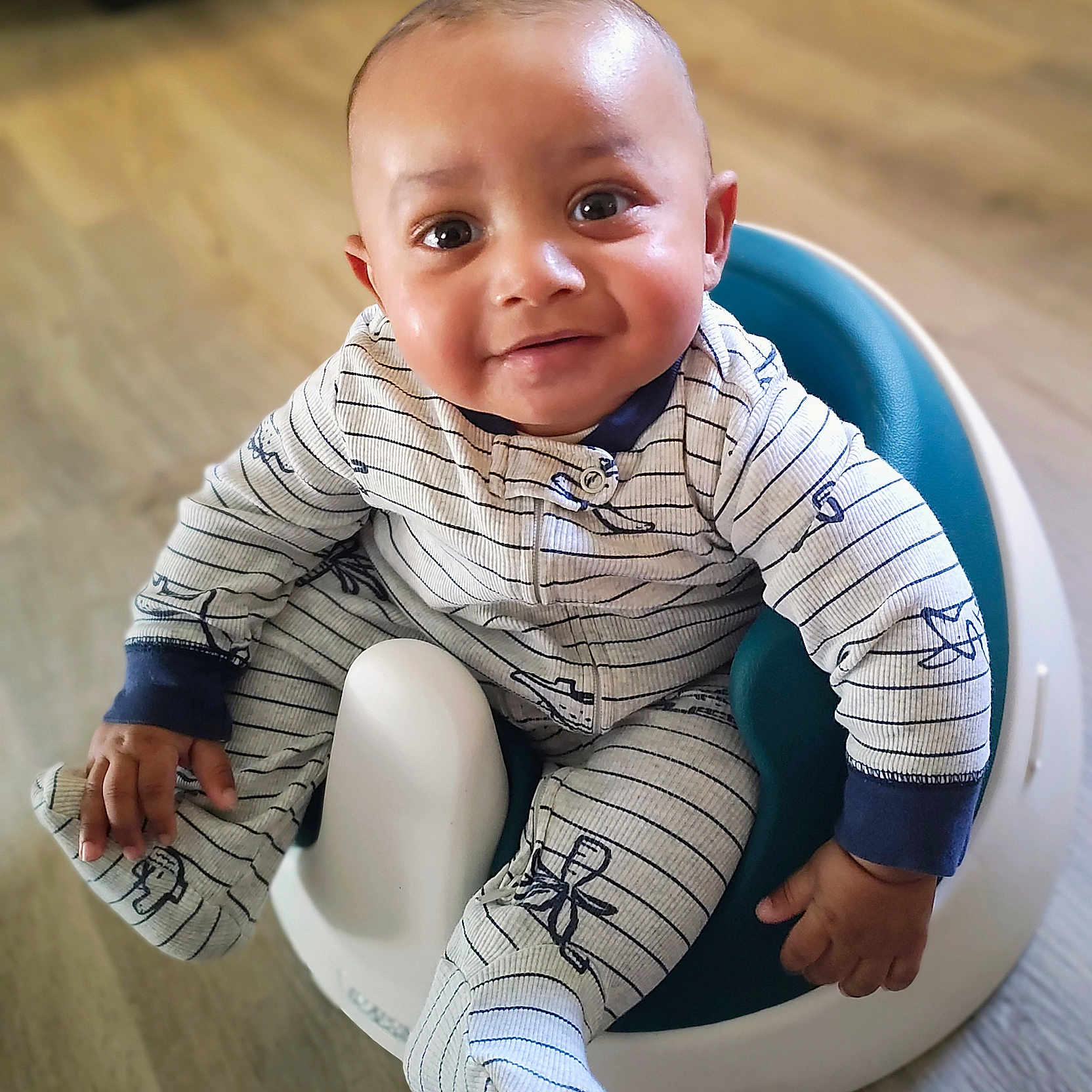 Azyias is registered to the contest to win money with this photo: baby, baby_seat, child, clothing, cute, face, floor, footwear, hand, happy, indoor, infant, looking_up, one_person, onesie, portrait, sitting, smiling, wooden_floor, young_child
