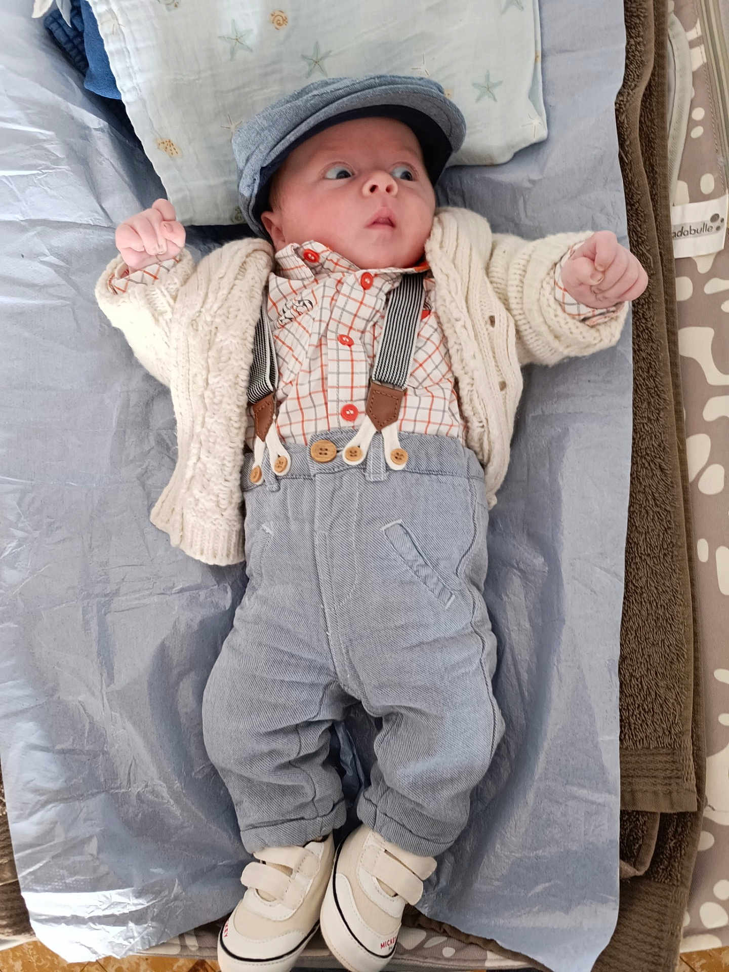 Moïse a rejoint le concours — aidez-le/la à gagner de superbes lots ! baby, infant, newborn, cap, cardigan, suspenders, button_up_shirt, trousers, sneakers, changing_mat, pillow, blanket, surprised_expression, eyes_wide, hands_up, cozy, plaid_shirt, knitwear, portrait, cute