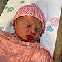 newborn, baby, sleeping, pink_hat, blanket, bed, infant, face, cozy, soft_texture, patterned_sheet, pastel_colors, peaceful, child, wrapped, resting, indoors, cute, headwear, closeup