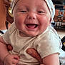 Hudson joined the competition — help win amazing prizes! baby, child, smiling, happy, onesie, head_wrap, indoor, living_room, adult_hand, furniture, television, person, cute, joyful, holding, infant, skin, face, expression, closeup