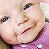 baby, smiling, close_up, face, purple_clothing, polka_dots, infant, cute, portrait, child, happy, soft_light, indoors, young_child, head, eyes, skin, cheeks, candid, expression