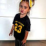 Kataleïa participe au concours pour gagner de l'argent avec cette photo : child, black_shirt, yellow_socks, hair_ribbons, shorts, standing, indoor, floor, playful, pose, decorative_wall_art, person, casual_clothing, footwear, expression, young_child, bright_colors, portrait, smile, hair