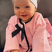 Lyana a rejoint le concours — aidez-le/la à gagner de superbes lots ! baby, child, smiling, pink_coat, headband, flower, black_bow, couch, seated, happy, portrait, infant, cute, clothing, fashion, indoors, person, hands, face, toddler