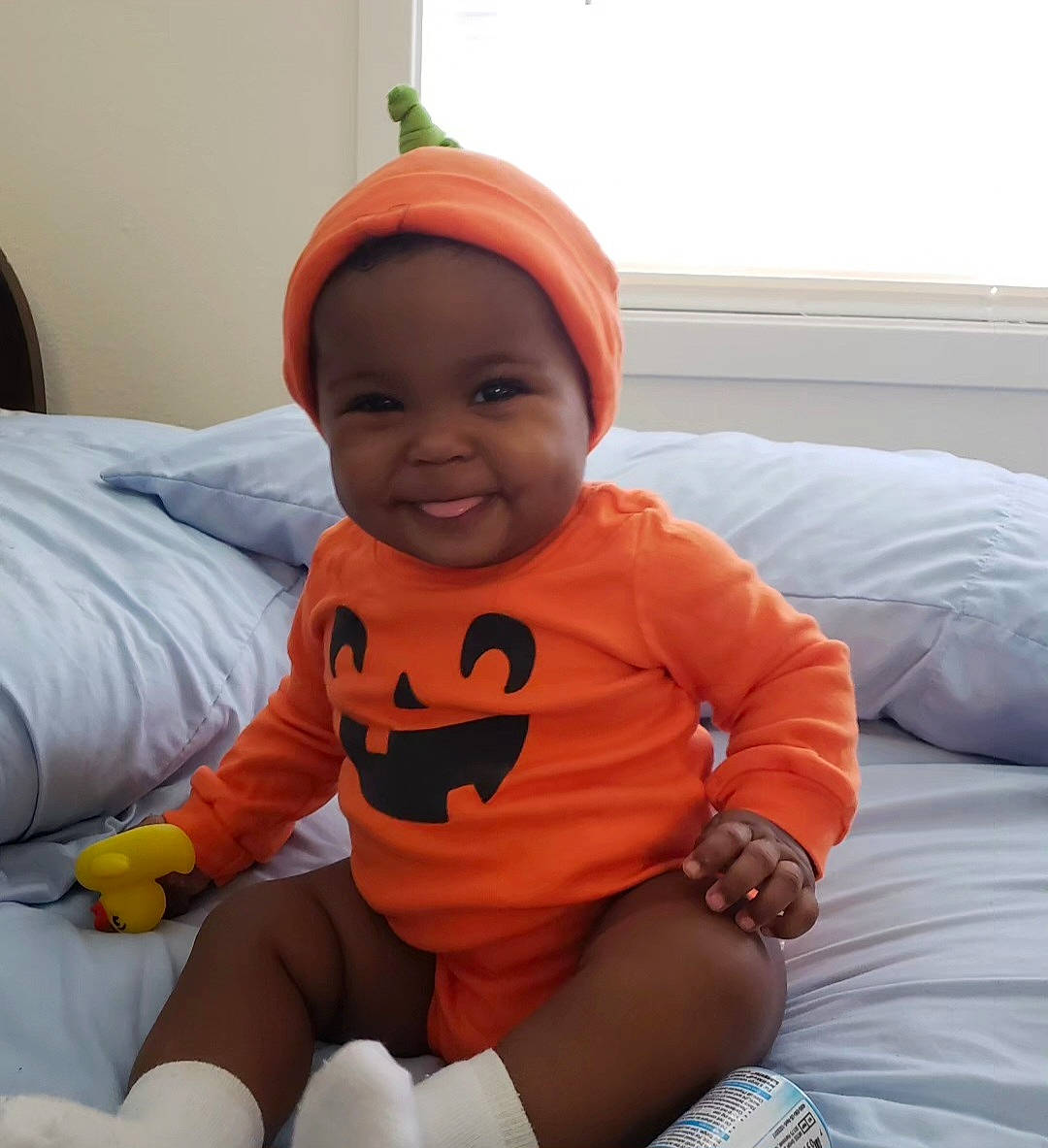 Azariah is registered to the contest to win money with this photo: arm, baby, baby_toddler_clothing, cap, cheek, child, comfort, face, facial_expression, fun, happy, joy, knee, mouth, orange, person, skin, sleeve, smile, t_shirt
