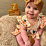 Renley is registered to the contest to win money with this photo: baby, infant, smiling, headband, dress, orange, checkered, wooden_blocks, age_blocks, fluffy_blanket, cute, sitting, indoors, milestone, child, portrait, happy, face, hands, feet