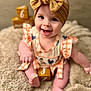 baby, child, smiling, headband, bow, dress, orange, white, checkered, animal_print, sitting, blanket, fluffy, wooden_blocks, numbers, months, indoor, cute, portrait, happy