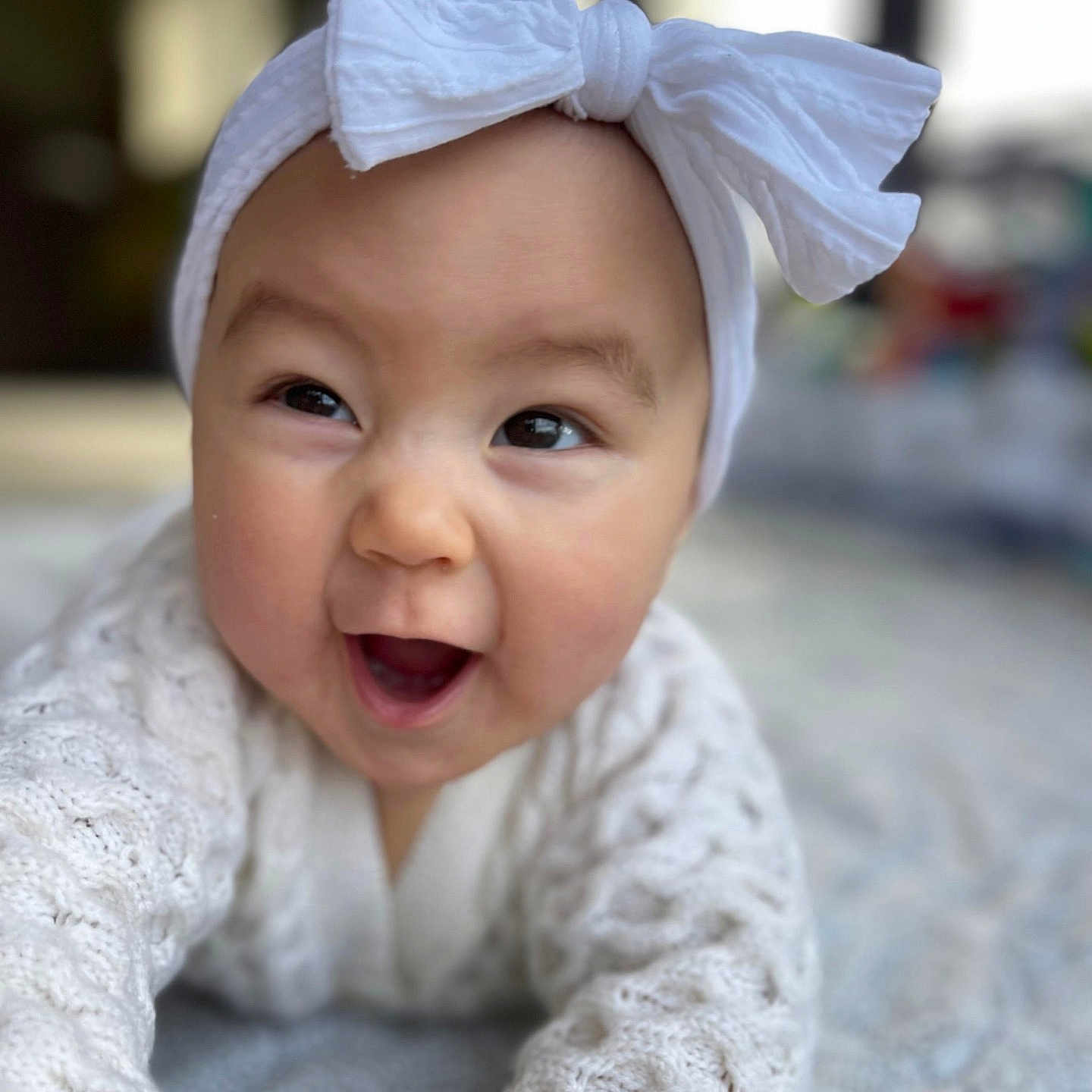 Savona joined the competition — help win amazing prizes! baby, child, closeup, crawling, cute, expressive, face, happy, headband, headwear, indoors, infant, knitted_sweater, patterned_surface, playful, portrait, smiling, soft_light, white_bow, young_child