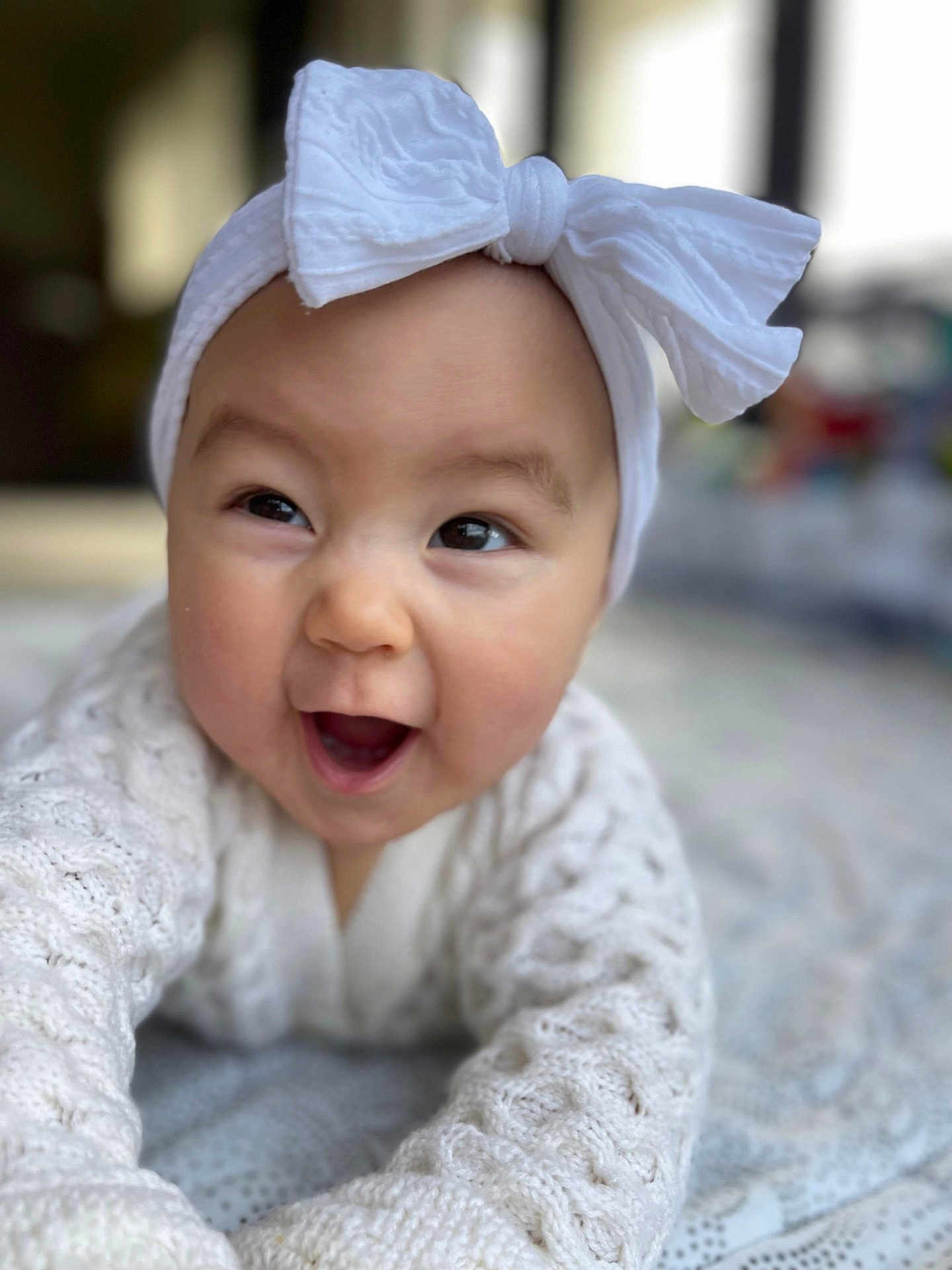 Savona joined the competition — help win amazing prizes! baby, smiling, headband, white_bow, knitted_sweater, crawling, face, happy, infant, cute, child, indoors, soft_light, patterned_surface, closeup, portrait, young_child, headwear, expressive, playful