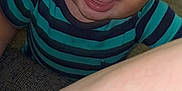 Junior is registered to the contest to win money with this photo: baby, child, smiling, curly_hair, striped_shirt, blue_shirt, green_shirt, face, eyes, mouth, tongue, arm, skin, indoor, candid, closeup, happy, person, infant, portrait