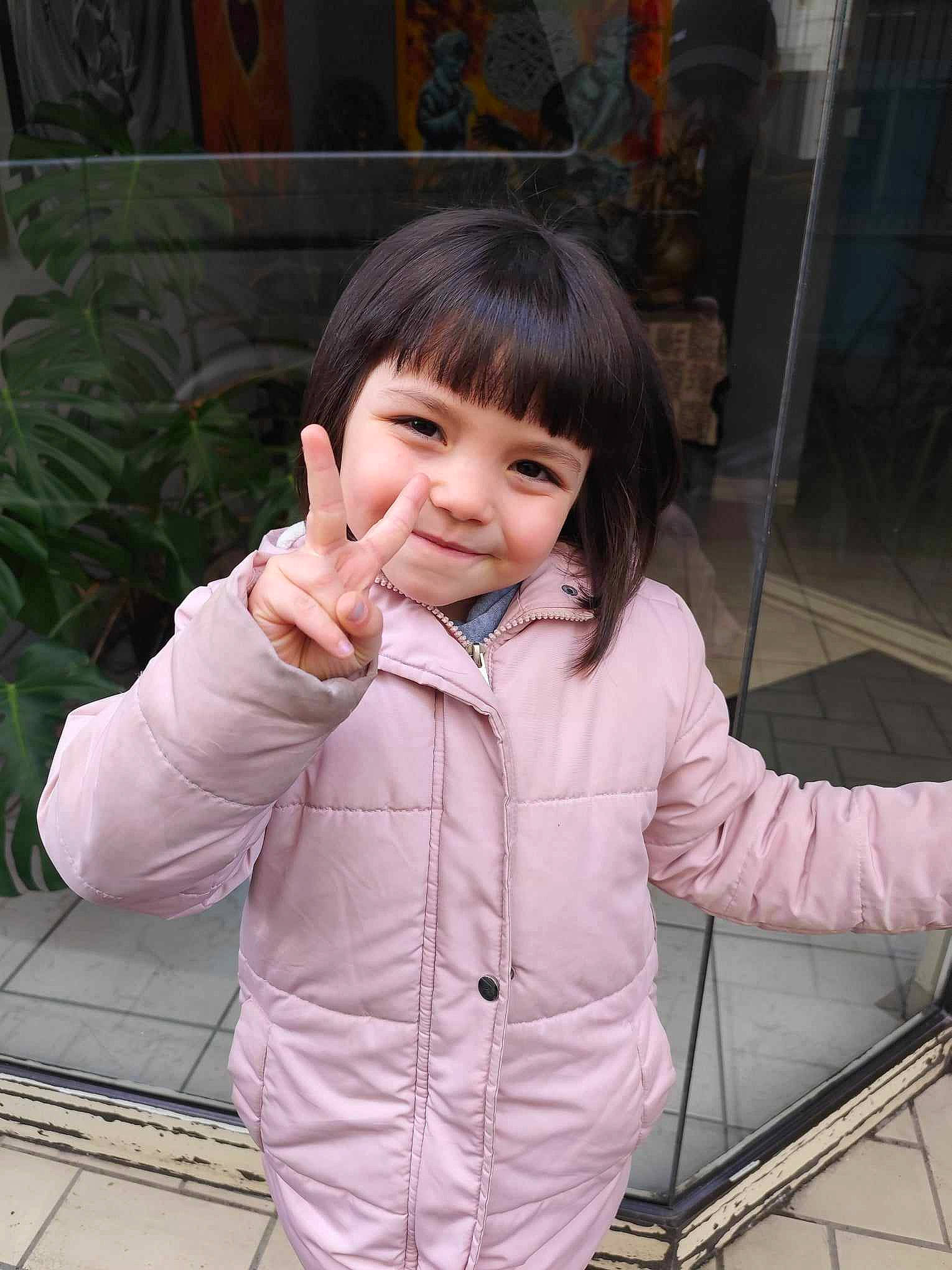 Louna participe au concours pour gagner de l'argent avec cette photo : bangs, cheek, child, chin, facial_expression, fun, gesture, happy, hoodie, jacket, joy, nose, person, plant, portrait_photography, skin, sleeve, smile, thumb, toddler