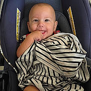 Tiberius joined the competition — help win amazing prizes! baby, infant, child, smiling, car_seat, blanket, striped_blanket, portrait, indoors, seated, happy, face, hand, chewing, clothing, fabric, safety_seat, vehicle, close_up, casual_photo