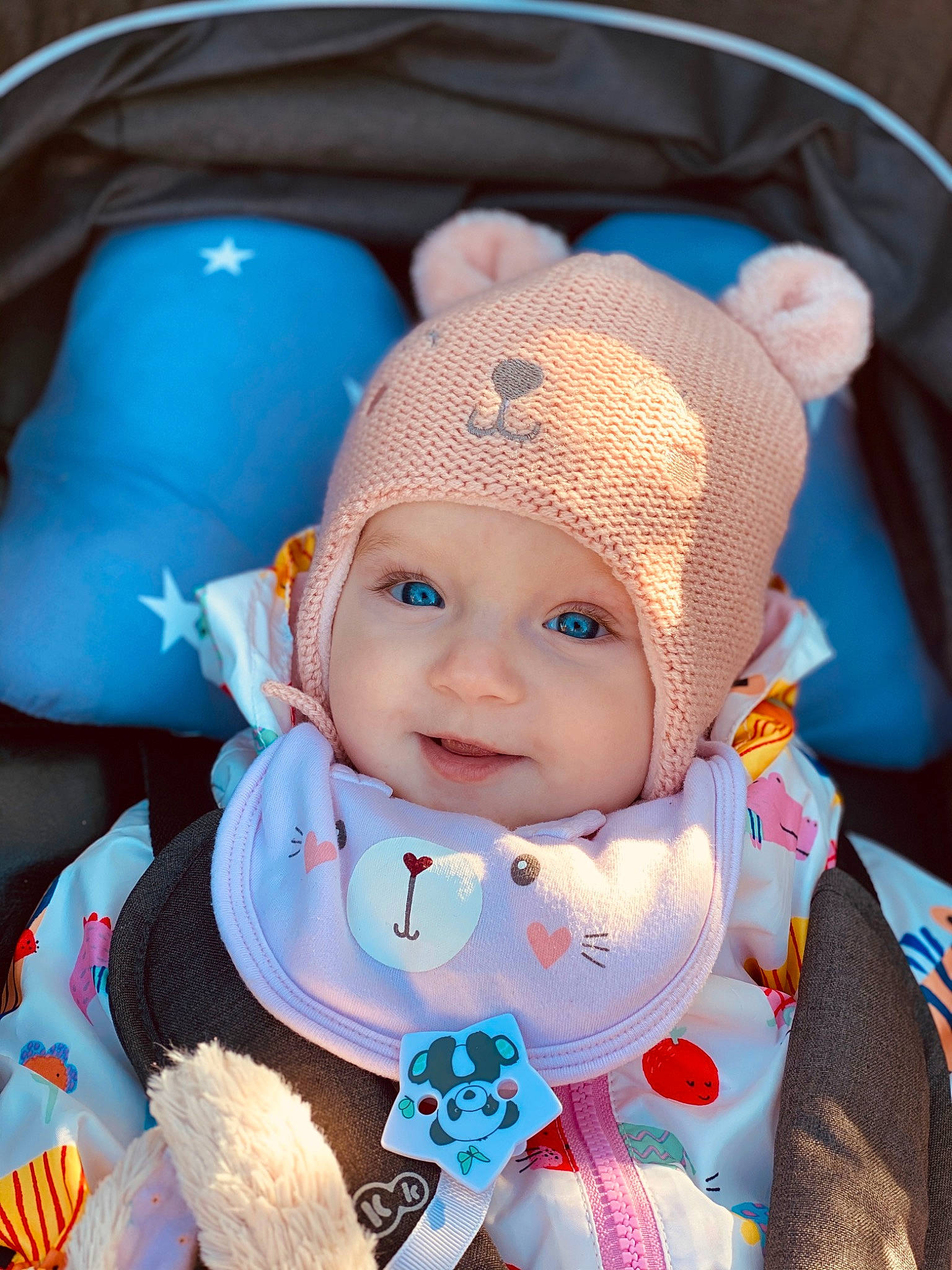 Kataleya participe au concours pour gagner de l'argent avec cette photo : baby, baby_products, baby_toddler_clothing, beanie, bib, cap, cheek, child, comfort, dress, electric_blue, fashion_accessory, fun, happy, headgear, headwear, iris, knit_cap, person, sitting