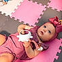 baby, child, toy, headband, pink, purple, foam_mats, floor, indoor, playtime, cute, infant, girl, clothing, hand, expression, blue_eyes, pacifier, colorful, soft_toys