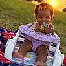 baby, child, infant, outdoor, sunset, grass, baby_seat, toy, bow, blanket, hand, playful, smile, cute, sunlight, nature, portrait, sitting, warm_light, happy