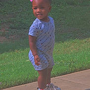 Donna joined the competition — help win amazing prizes! toddler, child, sidewalk, grass, romper, sneakers, footwear, outdoor, daylight, smiling, portrait, person, casual_clothing, headwear_overlay, heart_emojis, urban, concrete, curb, cute, standing