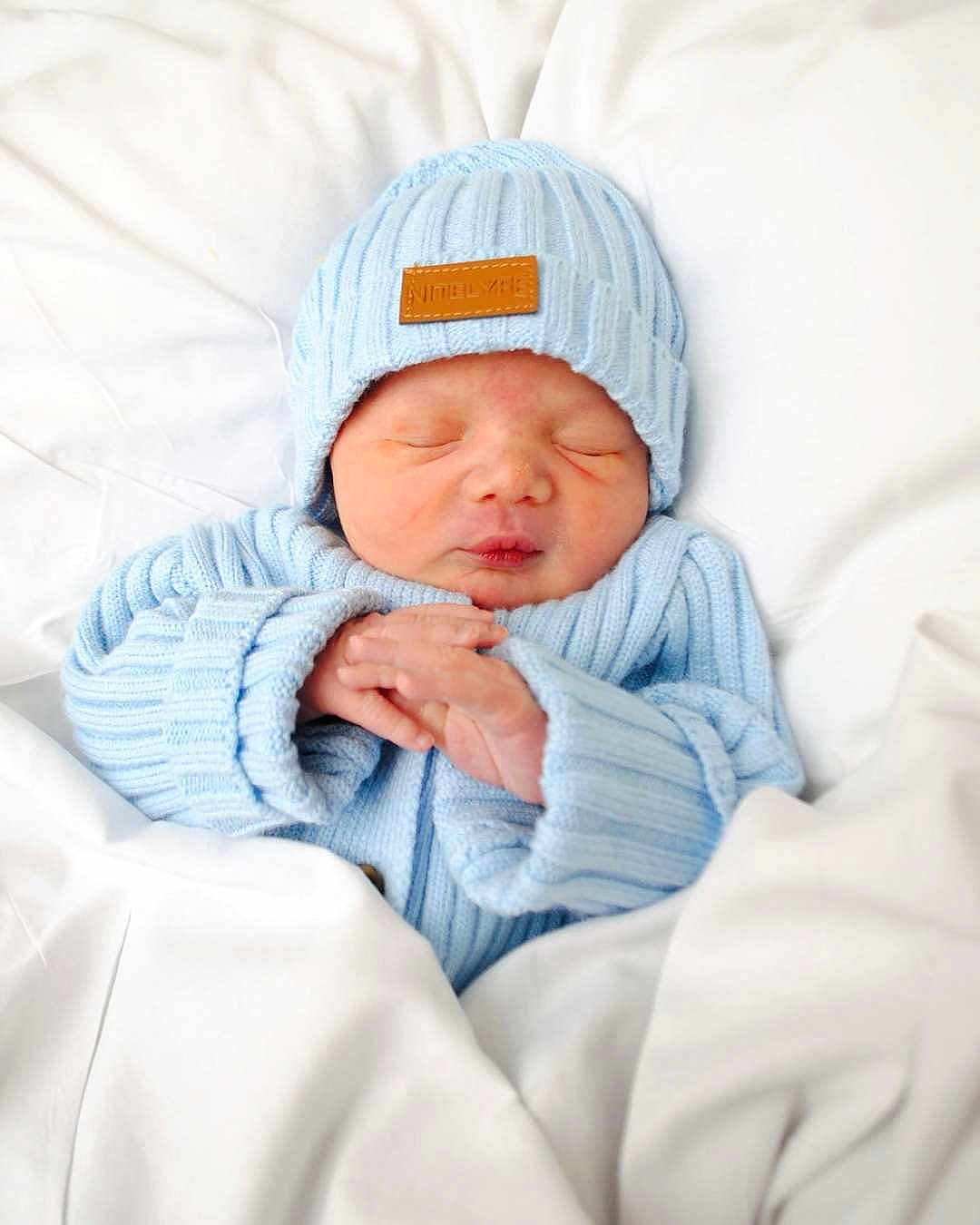 Ezekiel is registered to the contest to win money with this photo: baby, newborn, infant, sleeping, beanie, hat, knitwear, blue_clothing, blanket, bedding, swaddle, tiny_hands, closed_eyes, peaceful, portrait, closeup, soft_texture, nursery, skin, cozy