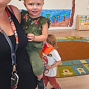 Harley joined the competition — help win amazing prizes! toddler, child, adult, indoor, playroom, classroom, smiling, pigtails, green_clothing, super_mario, orange_cup, rug, wall_mural, wooden_floor, book_shelf, toy_room, kids, happy, casual_clothing, education