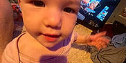 Willow is registered to the contest to win money with this photo: baby, child, infant, carpet, television, cartoon, pink_clothing, hand, face, indoor, carpet_floor, person, furniture, screen, entertainment, young_child, candid, blurry, shadow, toy