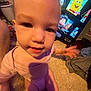 baby, child, infant, carpet, television, cartoon, pink_clothing, hand, face, indoor, carpet_floor, person, furniture, screen, entertainment, young_child, candid, blurry, shadow, toy