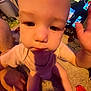 baby, child, hand, carpet, television, cartoon, indoor, person, clothing, pink, face, adult_hand, sitting, closeup, screen, toy, floor, curious, home, infant