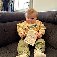 Mélio participe au concours pour gagner de l'argent avec cette photo : baby, child, coat, couch, cozy, cute, door, happy, indoor, infant, milestone_card, pants, portrait, sitting, smile, socks, sofa, soft_lighting, sweatshirt, window