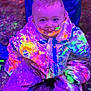 Henry is registered to the contest to win money with this photo: child, toddler, neon_paint, fluorescent, blacklight, paint_splatter, messy, smiling, tongue_out, protective_suit, colorful, portrait, sitting, indoor, party, playful, face_paint, short_hair, eye_contact, hands_in_lap