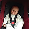 Ambre a rejoint le concours — aidez-le/la à gagner de superbes lots ! baby, car_seat, child, infant, seat_belt, white_clothing, red, black, sitting, strapped_in, cute, expression, indoors, person, young_child, safety, car, transportation, newborn, comfort