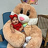 Ivy is registered to the contest to win money with this photo: baby, child, red_bow, red_clothing, stuffed_animal, easter_bunny, plush, smiling, indoor, chair, carpet, cute, happy, person, costume, toy, face, hand, footwear, cozy