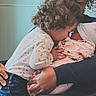 toddler, newborn, baby, child, curly_hair, floral_blanket, swaddled, kissing, family, love, affection, indoor, holding, person, closeup, intimate, caring, parent, sibling, cozy