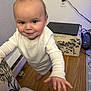 Amelia joined the competition — help win amazing prizes! baby, child, indoor, white_clothing, smiling, floor, wooden_floor, chair, floral_pattern, ottoman, laptop, pacifier, hand, face, person, cute, curious, standing, wall, power_outlet
