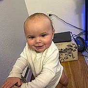Amelia joined the competition — help win amazing prizes! baby, child, smiling, indoor, white_clothing, standing, furniture, floor, wooden_floor, face, hands, barefoot, wall, power_outlet, toy, laptop, cable, pattern, person, home