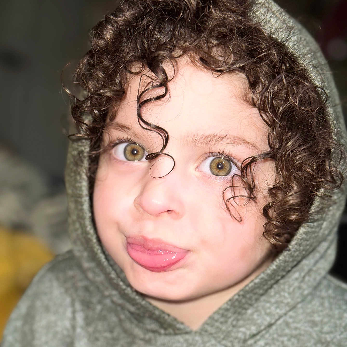 Zenyah is registered to the contest to win money with this photo: child, closeup, curly_hair, cute, expression, eyelashes, eyes, face, funny_face, headwear, hoodie, indoors, light, person, playful, portrait, skin, smile, tongue_out, young