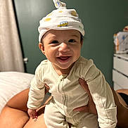 Sergio joined the competition — help win amazing prizes! baby, child, smiling, onesie, hat, infant, happy, person, indoor, bedroom, adult_hand, skin, face, cute, joy, childcare, apparel, portrait, holding, warm