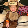 Sergio is registered to the contest to win money with this photo: baby, child, costume, moose, fuzzy, smiling, happy, bed, pillow, plush, indoor, cute, clothing, face, person, infant, seated, warm, funny, cozy