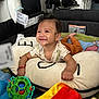 Sergio is registered to the contest to win money with this photo: baby, child, smiling, toy, plush_pillow, blanket, indoor, home, happy, infant, colorful, playpen, clothing, face, person, furniture, blurred_background, sitting, cute, candid