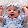 baby, infant, smile, happy, headband, blue_dress, floral_pattern, hands, feet, lying_down, white_rug, cute, child, portrait, closeup, person, skin, expression, indoors, playful